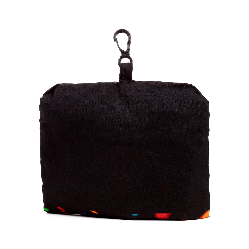 Head-on view of a compact black foldable shopping bag pouch, featuring a dark metallic carabiner clip at the top and hints of a vibrant multi-coloured pattern along the lower edge.