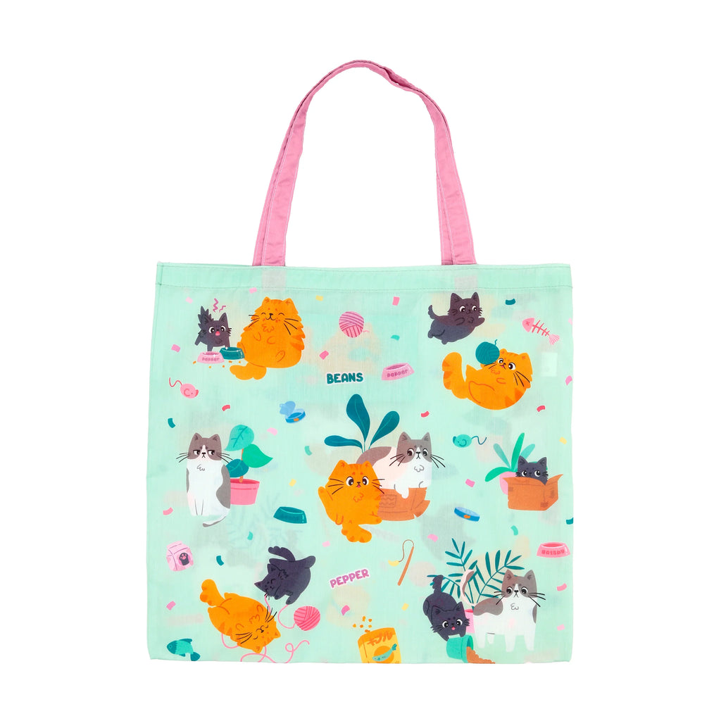 Front view of a mint green shopping tote bag with pink handles, featuring a playful pattern of colourful cartoon cats, fish, and yarn.