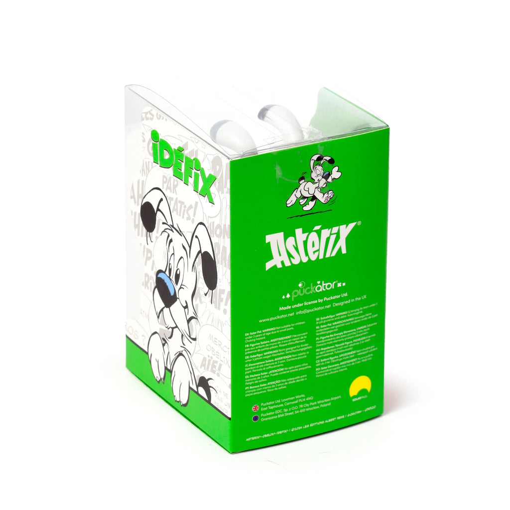Angled view of a packaged Asterix Idefix (Dogmatix) Solar Powered Pal, featuring a green and white box with cartoon dog illustrations and a clear top revealing two white wobbly ears.