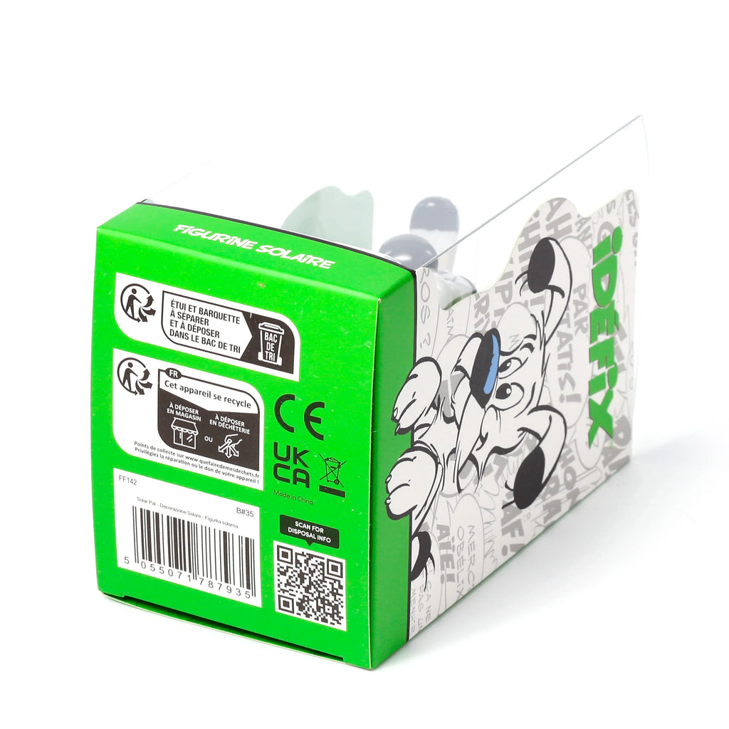 Angled view of an Idefix (Dogmatix) solar powered pal in its green and clear plastic packaging. The box displays 'FIGURINE SOLAIRE' text, recycling symbols, a barcode, and a graphic illustration of Idefix's head, with the grey and white dog figure partially visible inside.