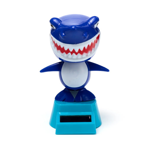 Front view of a blue and white Solar Pal shark toy, showing its wide open mouth with red gums and jagged white teeth, standing on a turquoise base with a solar panel.