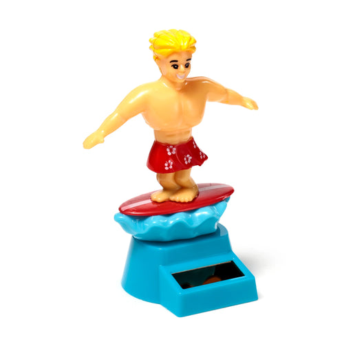 Front view of a Solar Pal surfer figure with blond hair and red shorts featuring white hibiscus flowers, standing on a red surfboard above a blue wave, powered by a solar panel on its blue base.
