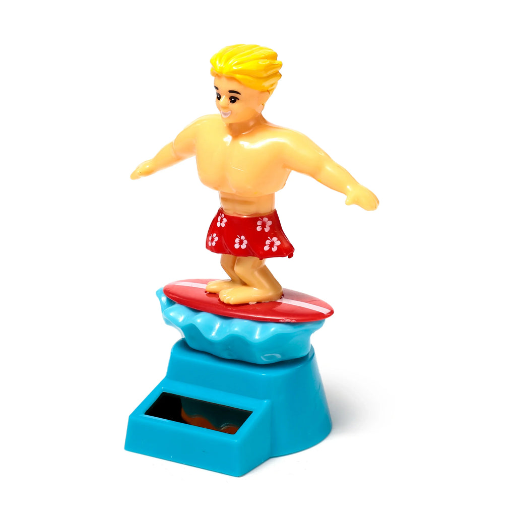 Front view of a Solar Pal surfer figurine with yellow hair, wearing red floral shorts, balancing on a red surfboard atop a blue wave and solar panel base.