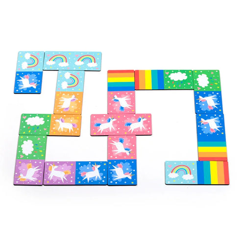 Angled view of a colourful kids' unicorn magic picture dominoes set, with pieces depicting white unicorns, rainbows, and clouds laid out on a white background.