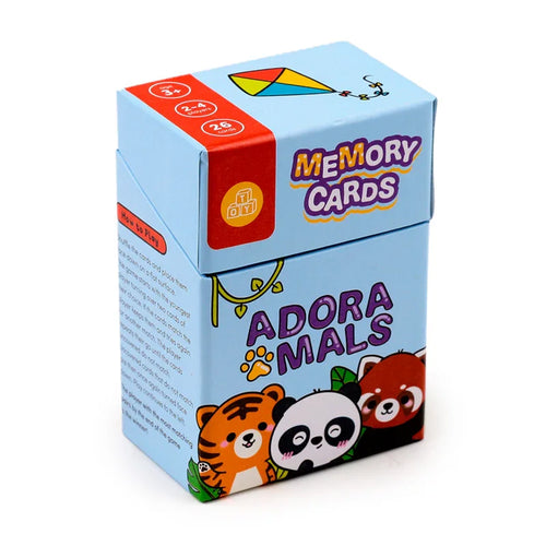 Angled view of a light blue kids memory card set box, depicting the 'Adoramals' title with a paw print, illustrations of a tiger, panda, and red panda on the front. The top shows 'Memory Cards' text and a colourful kite, while a red band specifies '3+', '2-4 players', and '26 cards'. 'How to Play' instructions are visible on the side.