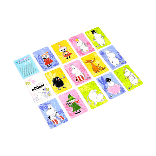 Angled view from above of a children's Moomin memory card set, displaying numerous colourful rectangular cards. Each card features a distinct Moomin character against yellow, pink, blue, or lime green backgrounds, alongside a visible instruction card outlining the game rules.