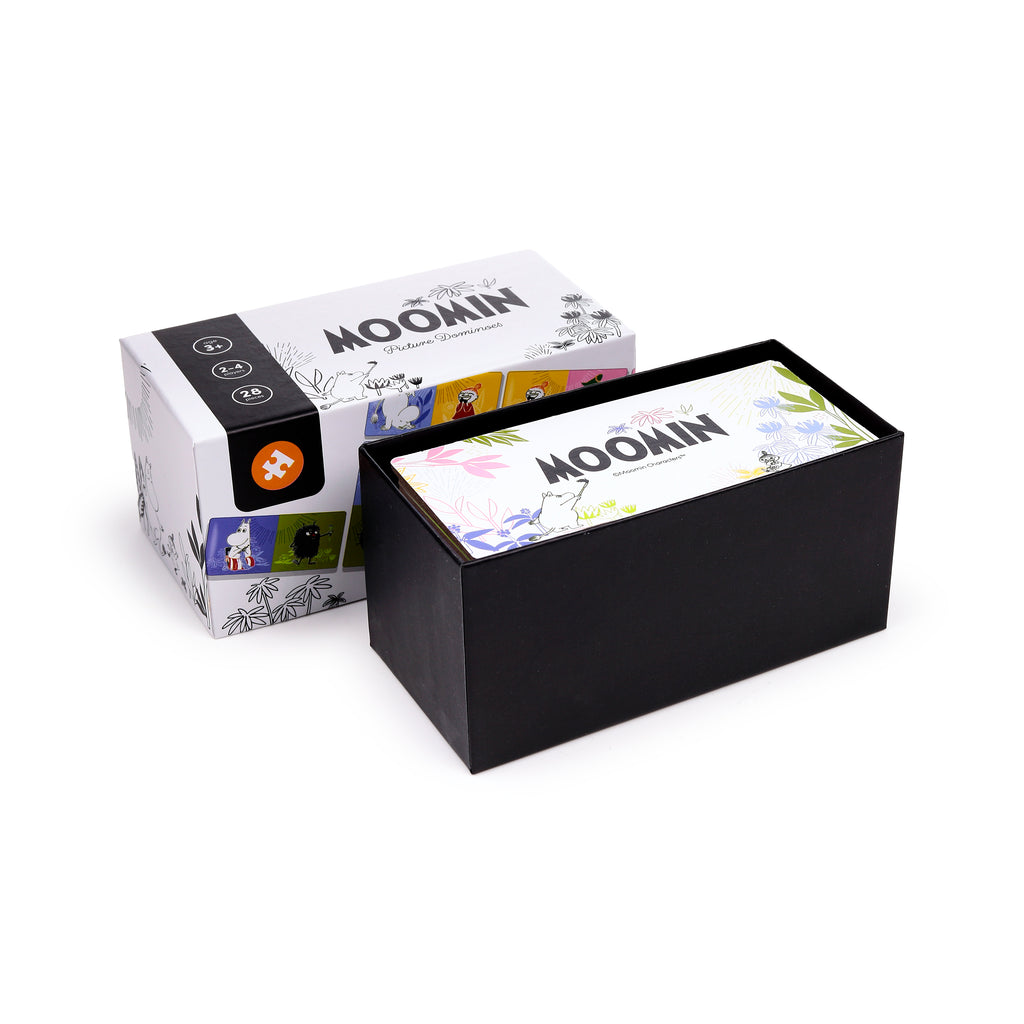 Angled view of an open Kids Moomin Dominoes Set box, with a white lid depicting Moomin illustrations and a black band detailing age 3+, 2-4 players, and 28 pieces. The black base contains picture dominoes, one of which shows colourful Moomin artwork.