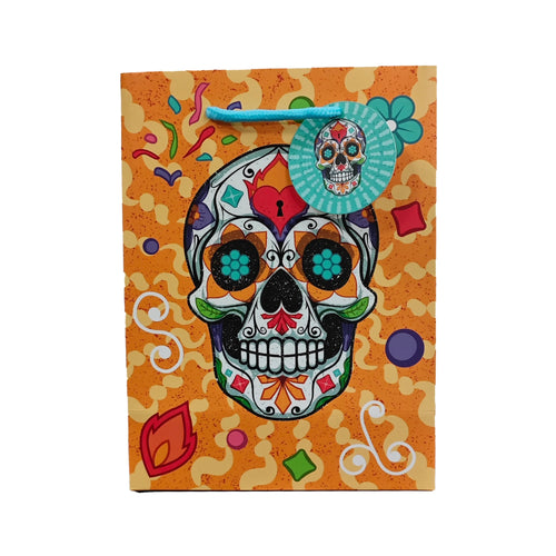 Front view of an orange Day of the Dead gift bag, depicting a vibrant sugar skull with teal eye detailing, blue braided handles, and a circular skull-patterned tag.