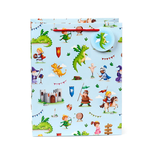 Front view of a large, light blue gift bag with a detailed 'Knights & Dragons' cartoon illustration. The design features various characters like knights, a princess, a wizard, and a Viking, alongside green and orange dragons, a castle, and medieval-themed elements. It has a red twisted rope handle and a round tag showing a green dragon.