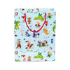 Front view of a large gift bag with red rope handles, featuring a light blue background printed with a lively knights and dragons theme, including castles, princesses, and wizards.