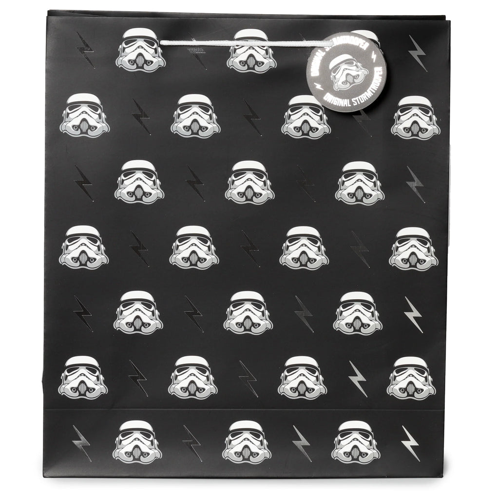 Front view of an extra large black gift bag patterned with white Stormtrooper helmets and silver lightning bolts, featuring white cord handles and a circular Stormtrooper tag.