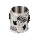Angled view of a silvery-grey decorative tankard, textured with black spider web and spider embellishments, showing its handle and stainless steel inner lining.