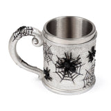 Angled view of a silver-coloured decorative tankard, featuring intricate black spider web designs and embossed black spiders on its textured surface and handle.