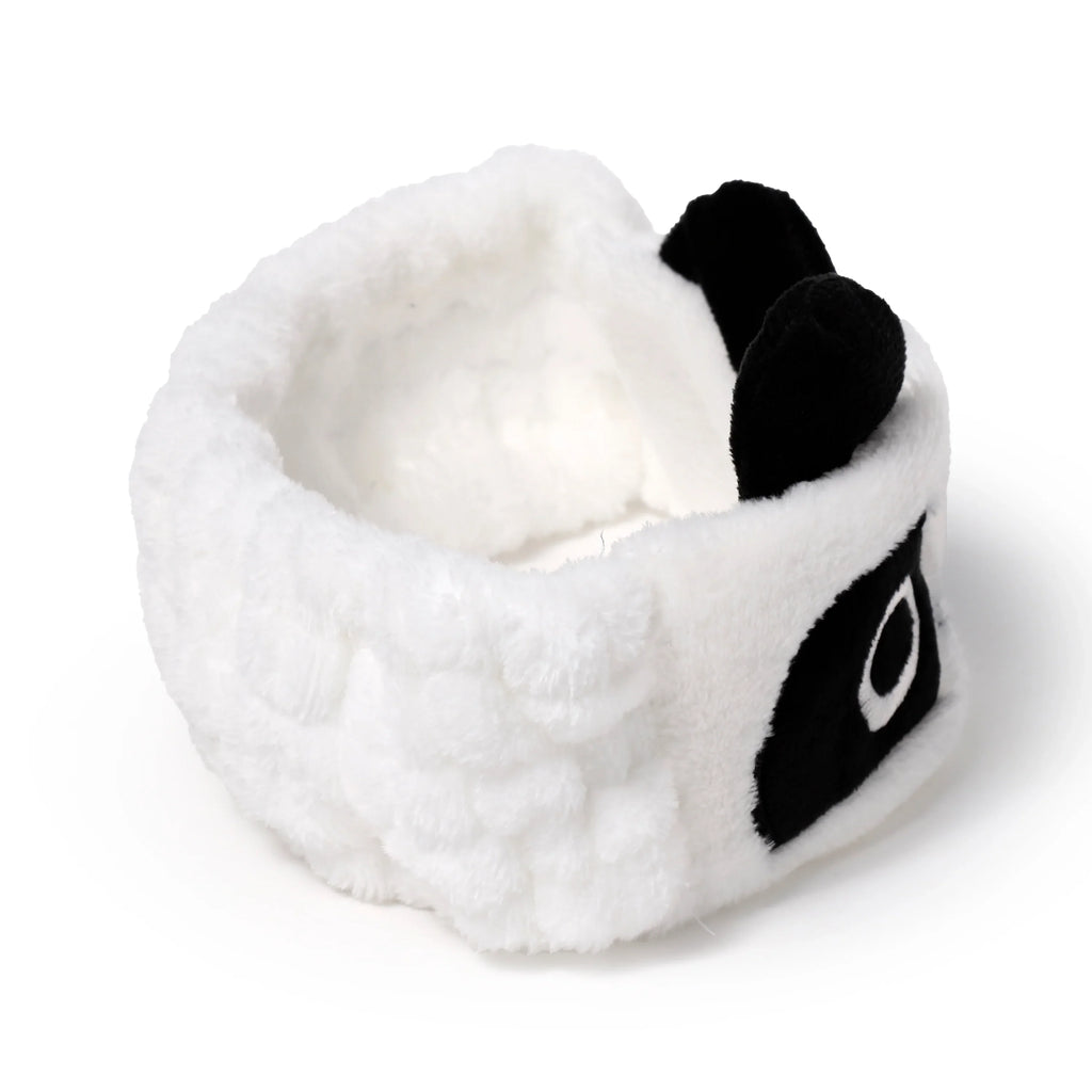 Elevated angled view of a white plush panda headband with black ears and eye patches.