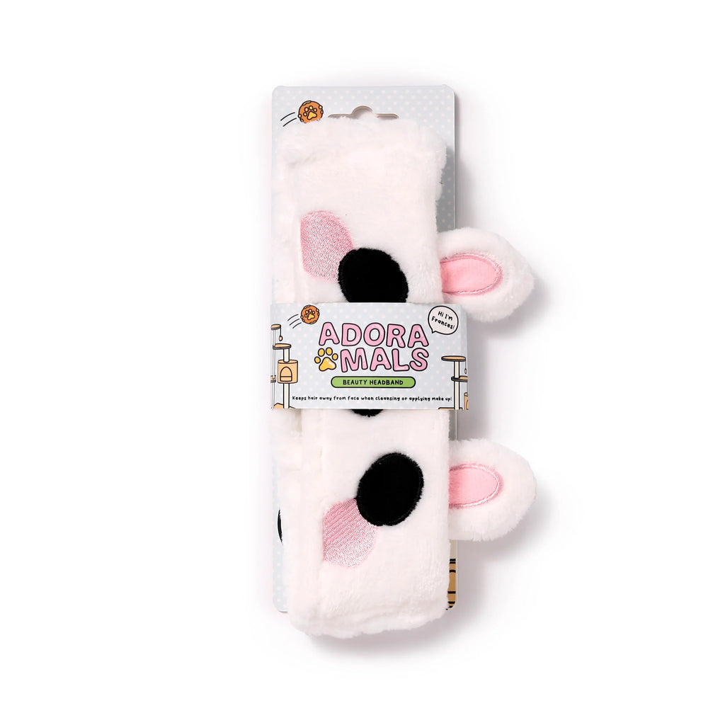 Front view of a white plush rabbit headband featuring pink inner ears, black spots, and pink embroidered cheek details, shown on its retail packaging.