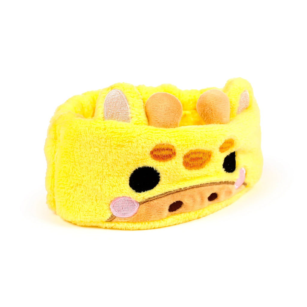 Yellow plush giraffe beauty headband, front view, with embroidered eyes, snout, pink cheeks, soft ears, and horns.