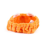 Angled view of an orange plush red panda headband with white and pink ears.