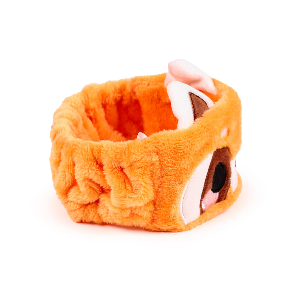 Angled view of an orange plush headband, featuring an embroidered red panda face with black eyes, a black nose, light pink snout, and two white and brown ears.