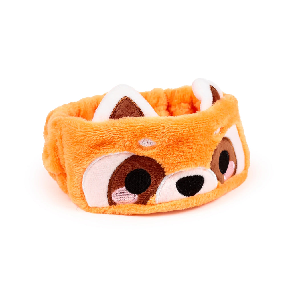 Angled view of an orange plush headband, featuring an embroidered red panda face with brown and white ears, black eyes, and pink cheek details, on a white background.