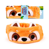 Front view of a fluffy orange red panda beauty headband, featuring embroidered eyes, nose, and upright ears. A second identical headband is visible behind it, partially encased in light blue retail packaging.