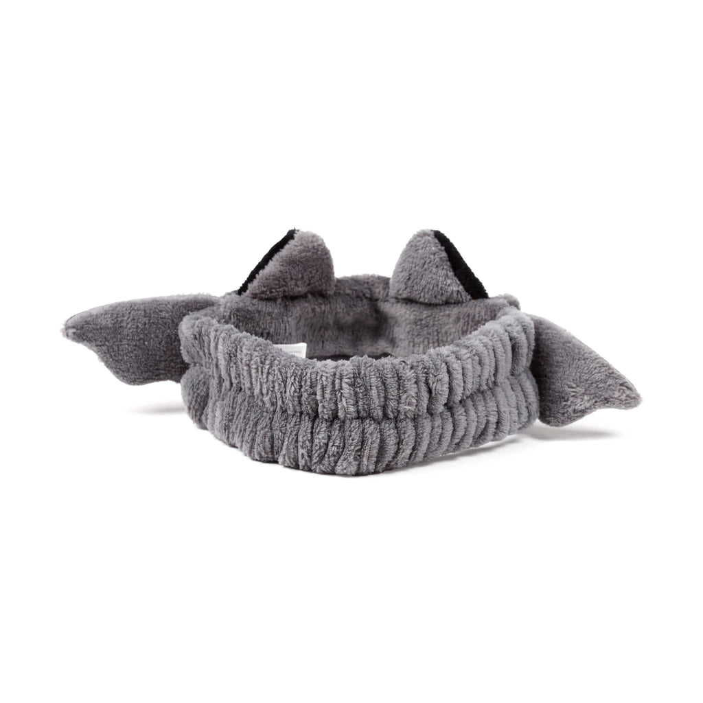 Angled view of a grey plush beauty headband, featuring bat ears with black inner details and grey bat wings.