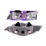 Plush grey Dexter the Bat beauty headband with black ears, embroidered eyes, nose, and pink cheeks. Displayed unpackaged and within purple retail packaging.