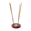 Angled view of a round, dark brown Sheesham wood incense holder and ash catcher. The top surface features a central gold-coloured Yin Yang inlay, surrounded by small star inlays. Four light brown incense sticks with purple tips are inserted into the holder.