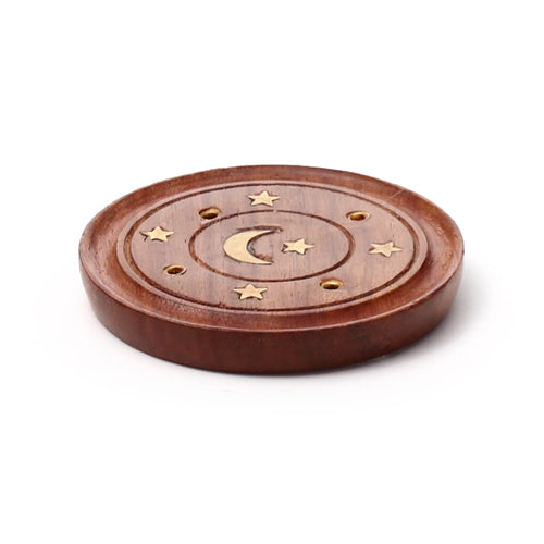 Angled view of a round dark brown Sheesham wood incense holder with a recessed ash-catching tray. The top surface features a brass crescent moon inlay, several brass star inlays, and multiple brass-lined holes for incense sticks and cones.