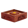 Elevated view of a Sheesham wood incense cone holder base, featuring a dark reddish-brown finish with intricate floral fretwork carved onto its exterior sides, and a central raised block with a golden-coloured metal cup.