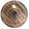 Overhead view of a round dark brown mango wood incense holder, featuring a black Hamsa symbol in the centre, surrounded by etched circular grooves. It has a central brass cone burner and twelve small brass holes for incense sticks.