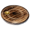 Angled view of a round, dark brown mango wood incense holder. It features a golden metal cup for cones, multiple small golden holes for incense sticks, lighter carved concentric rings, and a black Hamsa hand symbol in the centre.