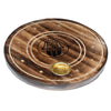 Angled view of a round dark mango wood incense holder, featuring a central black Hamsa symbol, concentric grooves, multiple small golden holes for incense sticks, and a larger golden cup for incense cones.