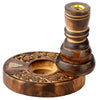 Angled view of a dark brown carved mango wood backflow incense burner, showing its circular base with intricate flower garden patterns, a golden metal incense holder at the top, and a small golden decorative motif.