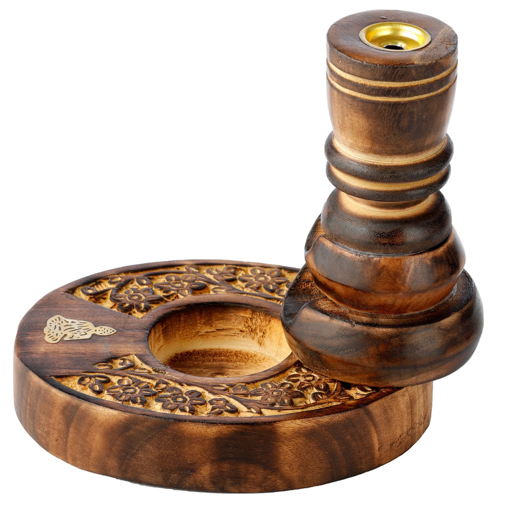 Angled view of a dark brown carved mango wood backflow incense burner, showing its circular base with intricate flower garden patterns, a golden metal incense holder at the top, and a small golden decorative motif.
