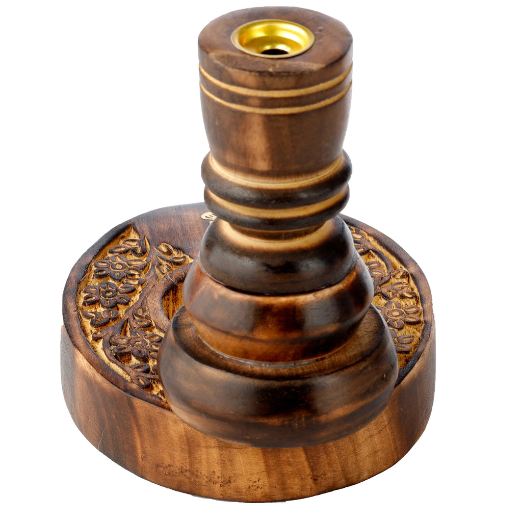 Angled view of a dark brown mango wood backflow incense burner, featuring carved floral garden patterns on its base and a golden top insert.