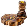 Angled view of a dark wooden incense burner with a carved Om symbol on its cloud-shaped base and a gold-coloured metal cup at the top of its turned pillar holder.