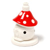 Front view of a ceramic fairy toadstool house incense cone burner, with a red cap featuring white spots, a white body with a small circular smoke hole, and a white cone holder at the top.