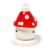 Angled view of a ceramic toadstool house incense cone burner, featuring a glossy red cap with white polka dots and a white base. Two circular ventilation holes are visible on the base, with a narrow opening at the top.
