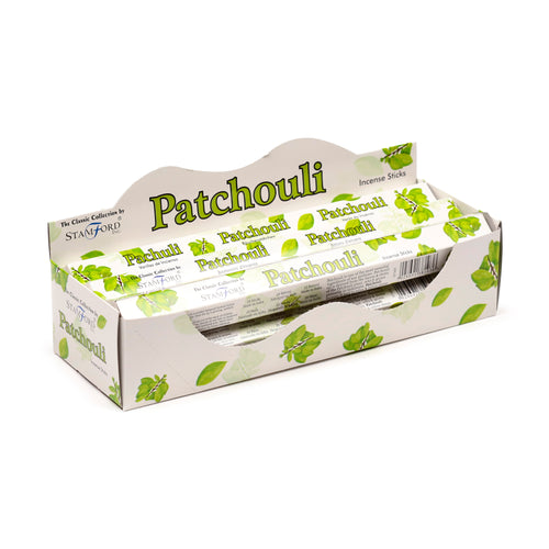 Angled view of an open white display box containing six individual packs of patchouli incense sticks. Each pack is decorated with green 'Patchouli' text and leaf illustrations, visible inside the box which has a wavy top edge.