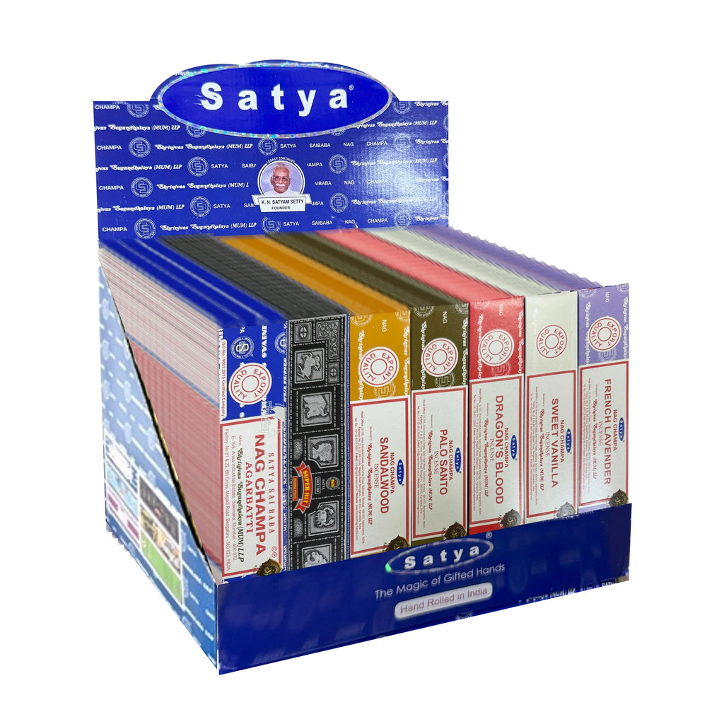 Angled view of a Satya Incense Sticks display box, showcasing a variety of colourful incense stick packets including Nag Champa, Sandalwood, Palo Santo, Dragon's Blood, Sweet Vanilla, and French Lavender.