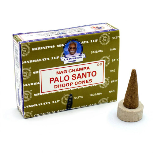 Angled view of an olive green and white box for Palo Santo incense cones, shown alongside a conical brown incense cone resting on a small, light-coloured round stand.