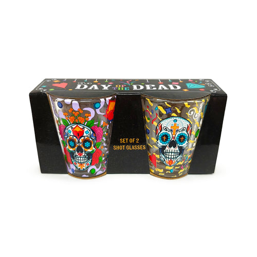 Front view of a set of two clear shot glasses, each adorned with vibrant, multicoloured Day of the Dead sugar skull and floral patterns, presented in a black display box.