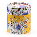 Angled view of a cylindrical jigsaw puzzle tube, featuring the 'Nectar Meadows Bee' design. The tube's white top section depicts colourful floral and bee illustrations, while its yellow lower section shows a large bee outline filled with flowers and scattered puzzle pieces.