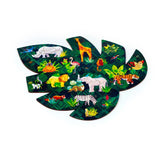 Overhead view of a fully assembled 130-piece wooden jigsaw puzzle, shaped like a large green tropical leaf. The puzzle features vibrant depictions of various jungle animals including a rhinoceros, giraffe, lion, elephant, tiger, and zebra, set against a dark green foliage background.
