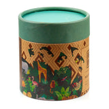 Angled view of cylindrical wooden jigsaw puzzle packaging with a dark green lid and base. The package features vibrant Animal Kingdom artwork of a giraffe, elephant, and jungle foliage, with a pattern of puzzle pieces above. The lid's visible surface is turquoise.