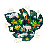 Overhead view of a wooden animal kingdom jigsaw puzzle, shaped like a large green leaf. The colourful puzzle features numerous wild animal and plant pieces, some fitted within the leaf, others lying detached around it.