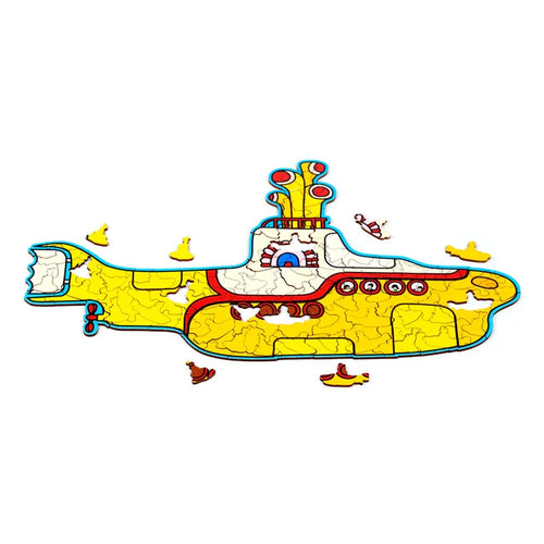 Side view of an assembled wooden jigsaw puzzle of The Beatles Yellow Submarine, featuring yellow, red, and blue colour details, with visible puzzle piece lines and several smaller loose yellow submarine-shaped pieces.