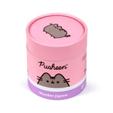 Angled view of a pink and lavender cylindrical 130-piece wooden jigsaw puzzle box. It features a Pusheen the cat illustration on the lid and side, with 'Pusheen' and 'Wooden Jigsaw' text.