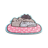Assembled 130-piece wooden jigsaw puzzle showing Pusheen the cat and a smaller grey cat sleeping in a pink polka-dot bed, with a light blue outline.