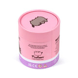 Angled view of a pink cylindrical 130-piece wooden jigsaw puzzle tube, featuring Pusheen the Cat illustrations on its lid and main body, alongside product description text and safety markings.